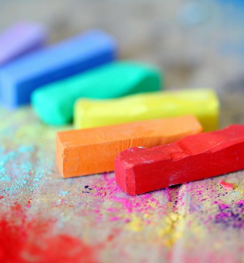 Vibrant pastel chalks on colorful splattered canvas, perfect for creative arts and crafts inspiration.