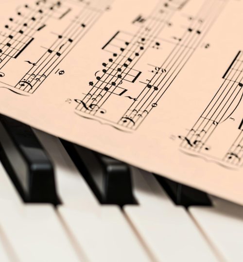 Black and white piano keys with a sheet of classical music creating a harmonious composition.