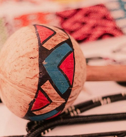 Traditional Brazilian maraca with vibrant patterns, showcased with background crafts.