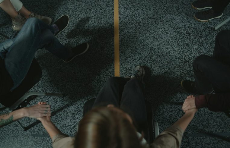 A diverse group of people holding hands in a circle, symbolizing support and unity in a mental health session.