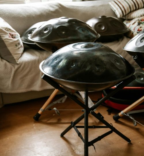 A set of handpans on stands in a cozy indoor setting with natural light streaming through a window.